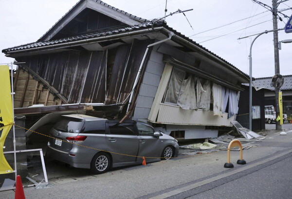 ​]5일 일본 이시카와현 스즈시에서 강진이 발생한 뒤 무너진 주택에 깔려 있는 자동차 한 대를 볼 수 있다. 이날 강한 지진이 발생했지만 쓰나미 위협에 대한 보고는 없었다.​