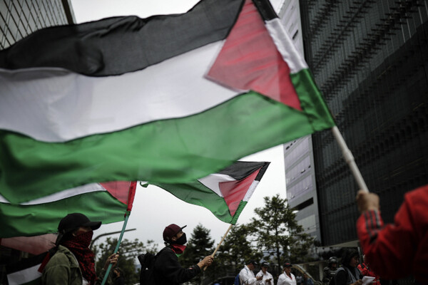 24일(현지시각) 콜롬비아 보고타에 있는 이스라엘 대사관 밖에서 친팔레스타인 시위 참가자들이 팔레스타인 깃발을 들고 시위하고 있다.