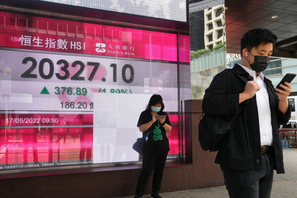 코로나19 예방을 위해 마스크를 착용한 홍콩 시민들이 17일 증권 시세 전광판 앞에서 스마트폰을 열심히 보고 있다. 2022.05.18