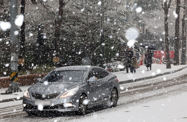 서울 전역에 눈이 내리고 있는 30일 서울 중구 명동 거리에서 시민들이 내리는 눈을 맞으며 발걸음을 재촉하고 있다.